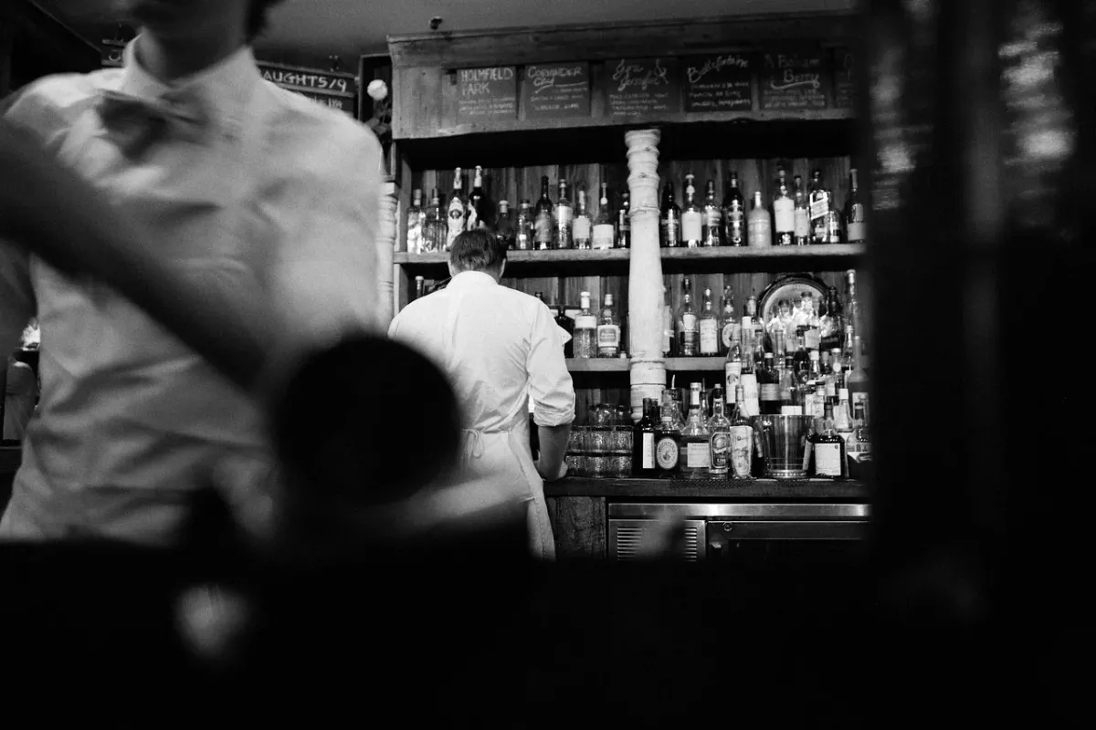 Kelner przygotowujący koktajl za eleganckim barem w restauracyjnym saloniku.